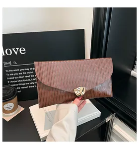 Detail einer braunen Umschlag-Clutch mit vertikaler Textur und goldener Metallschnalle
