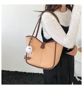 Detail view of contrast stitch tote bag with plush charm on a female model shoulder