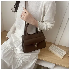 Detailed view of dark brown litchi leather bag with elegant oval metal twist lock