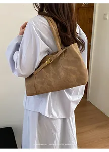 Side view of large retro dark brown tote bag with gold buckle on female model shoulder