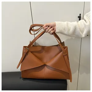 Detail of caramel brown handbag featuring unique geometric fold design and silver hardware