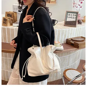 Vue détaillée du sac cabas blanc brillant avec cordon de serrage et bandoulière en chaîne