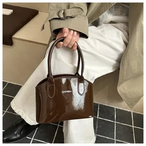 Detail of glossy brown patent leather handbag with FASHION metal logo and top handles