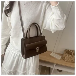Detail of dark brown leather handbag featuring lychee texture and gold metal twist lock