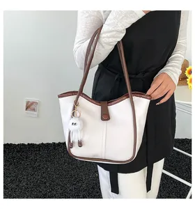 Detail view of cream and brown tote bag with cute plush charm on a model