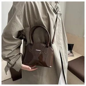 Close-up of dark brown glossy shell bag with Fashion print and cylindrical handle