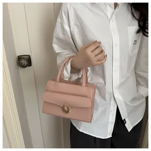 Detail of pink pebbled leather handbag with elegant gold twist lock and sturdy handle