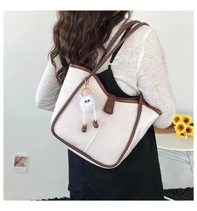 Detailed side view of white faux leather tote bag with brown straps and plush doll charm