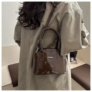 Detail of glossy brown patent leather handbag with silver Fashion metal logo lettering