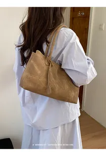 Brown retro oversized tote bag with long straps worn on the shoulder in a minimalist setting