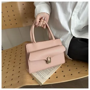Detailed view of pink pebble grain leather bag with golden metal lock on wooden chair