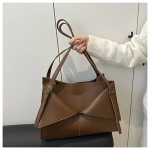 Detail of brown tote bag in matte faux leather with geometric triangular flap design