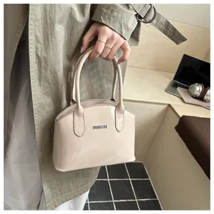 Detail of glossy beige shell handbag with silver metal logo and rounded handle
