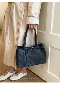 Detail of dark grey textured leather tote bag with elegant gold metal buckle and strap