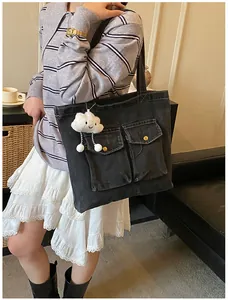 Detail of black denim tote bag with large front pockets and cloud plush charm