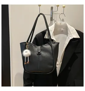 Close-up of black textured leather tote bag with a cute plush charm and snap buckle
