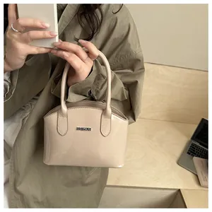 Detail of a beige patent leather handbag with a silver metal plate in a lifestyle setting