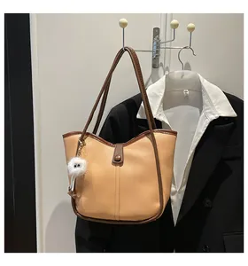 Chic khaki faux leather tote bag with dark brown trim and a plush monster charm