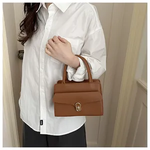 Detail of caramel brown crossbody bag showing fine lychee grain leather and golden metal lock