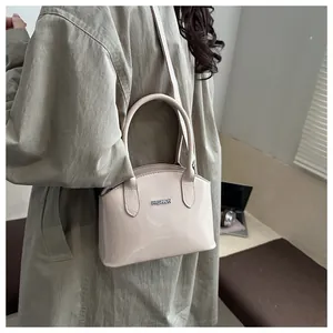 Close-up of beige glossy patent leather handbag with FASHION logo and smooth texture