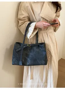 Detail of dark grey retro tote bag with textured finish and gold hardware accents