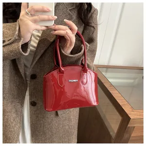 Detail of red glossy patent leather handbag with silver Fashion logo on brown blazer