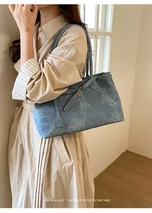Side view of a vintage blue textured tote bag worn by a model in a minimalist room