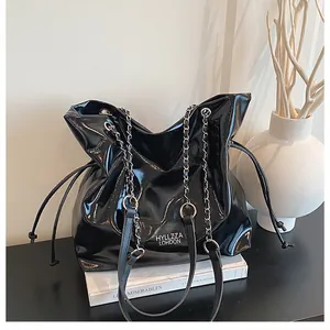 Détail du cabas en cuir verni noir avec chaîne argentée et texte HYLLZZA distinctif