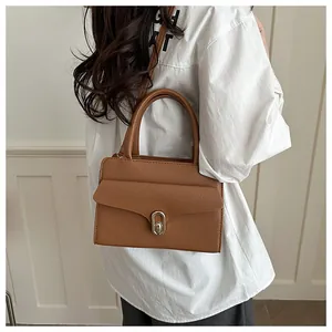 Detail of brown lychee grain leather handbag featuring a stylish metal twist lock closure