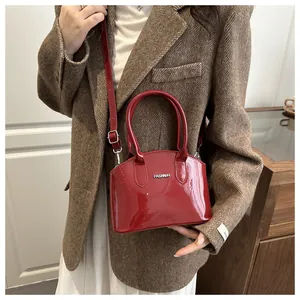 Red glossy patent leather shoulder bag with FASHION lettering shown on a model