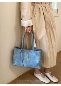 Blue vintage tote bag with textured leather shown on a model in a minimalist outfit