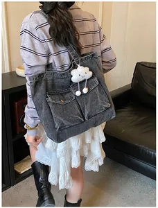 Detail of dark grey denim tote bag with metal buckle pockets and a cloud plush charm
