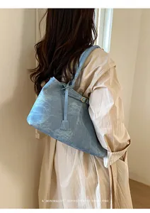 Detail of light blue denim texture tote bag with shoulder strap worn by a model