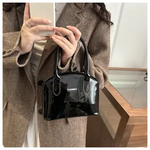 Detail of glossy black shell handbag with silver FASHION lettering and sleek finish
