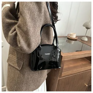 Detail of glossy black patent leather handbag with FASHION metal logo in a retro setting