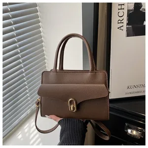 Detailed view of the brown lychee pattern leather handbag with gold metal twist lock