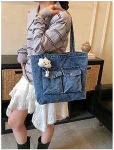Close-up of a blue denim tote bag featuring utility pockets and a plush cloud charm