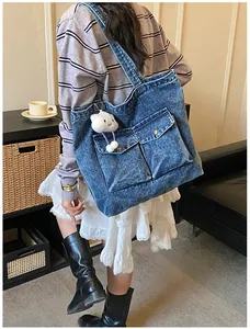 Blue denim tote bag with dual front pockets and white cloud charm shown on model