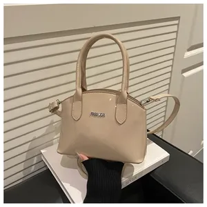 Close-up of beige patent leather handbag with silver Fashion logo and smooth glossy finish
