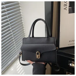 Detail of black pebbled leather texture and gold oval metal clasp on women handbag
