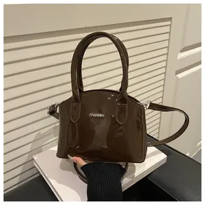 Close-up of a brown patent leather handbag featuring silver FASHION metallic lettering
