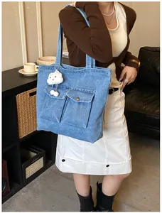 Detail of blue denim tote bag with cargo pockets and a cute cloud plush charm