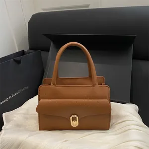 Brown litchi grain square handbag with gold twist lock on silk background
