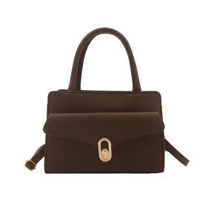 Dark brown leather square handbag with golden oval twist lock and adjustable crossbody strap