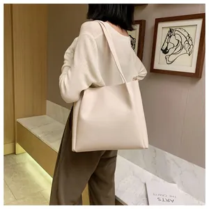 Fashionable beige large capacity tote bag shown on a model in a minimalist room