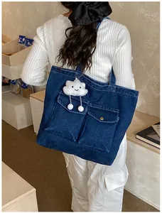 Detail of blue denim tote bag with two front pockets and a plush cloud charm for students