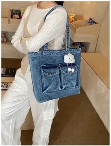 Detail of blue denim tote bag with large front pockets and white cloud plush charm