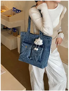 Detailed shot of large capacity washed denim tote bag with plush cloud pendant and front pockets