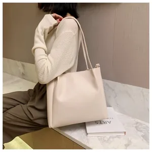 Minimalist beige leather tote bag shown on model with shoulder strap for daily commuting