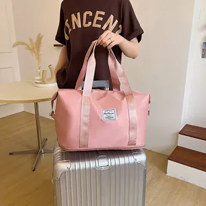 Pink waterproof travel bag showing the trolley sleeve functionality on a silver suitcase